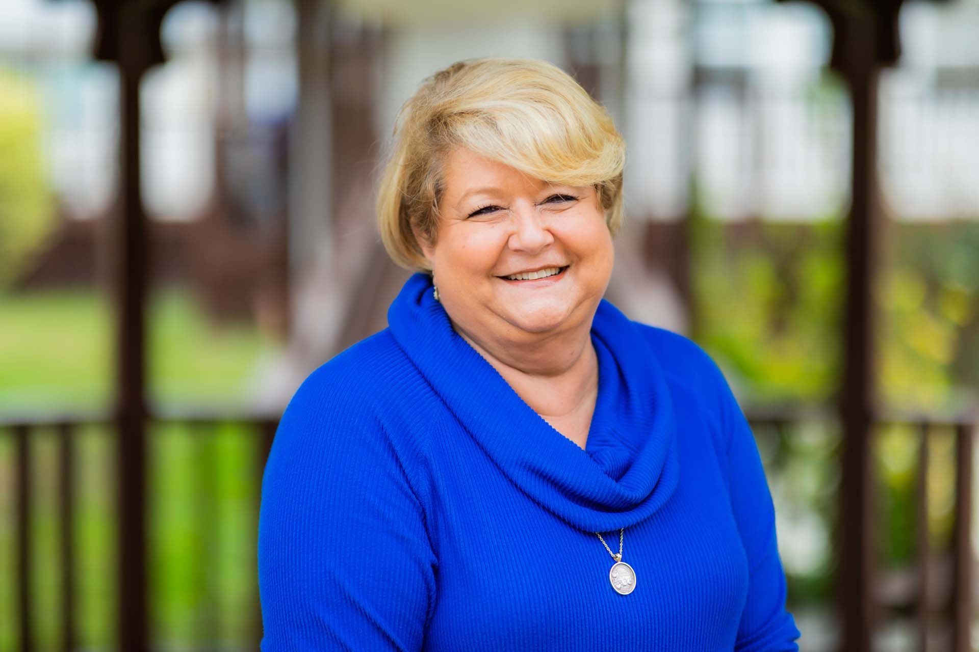 A woman in a blue sweater is smiling for the camera.