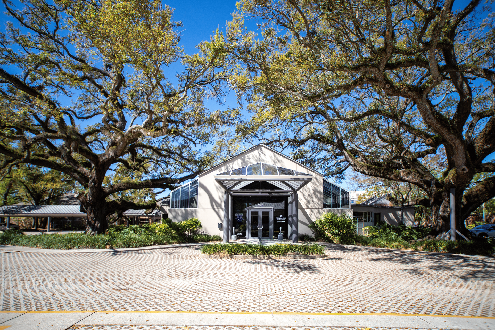 A large white building is surrounded by trees on a sunny day.