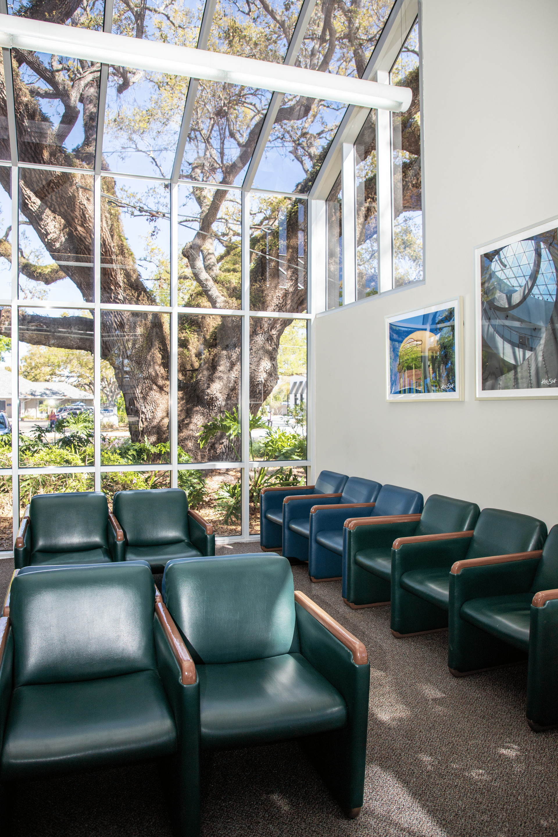 A waiting room with green chairs and a large window.
