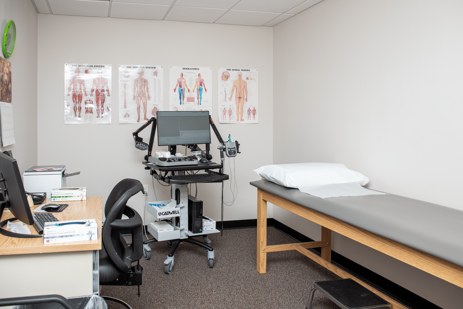 A doctor 's office with a couch , desk , chair and computer.