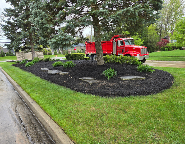 A red dump truck is parked in a lush green yard