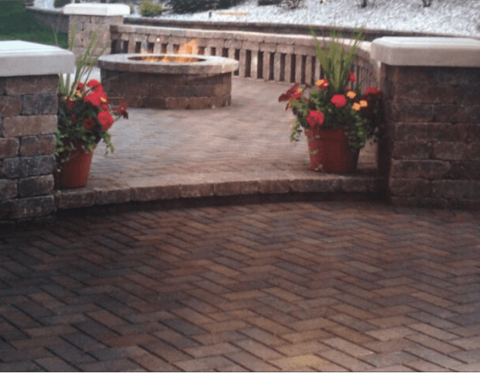 A brick patio with potted plants and a fire pit