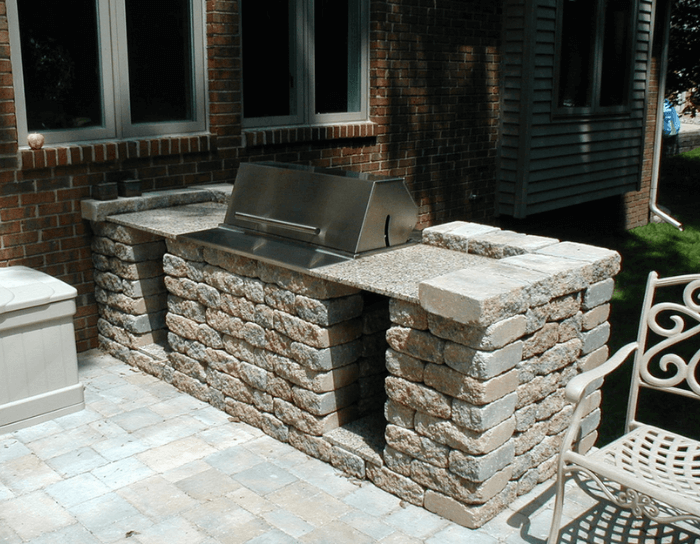 A brick patio with a grill and a chair