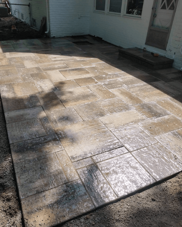 A patio with a lot of tiles on it is being built in front of a house.