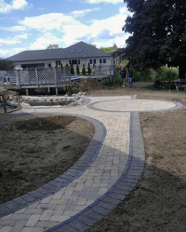 A brick walkway with a house in the background