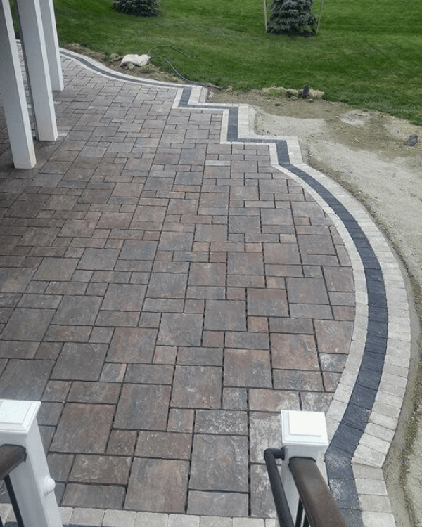 A brick walkway with stairs and a lawn in the background