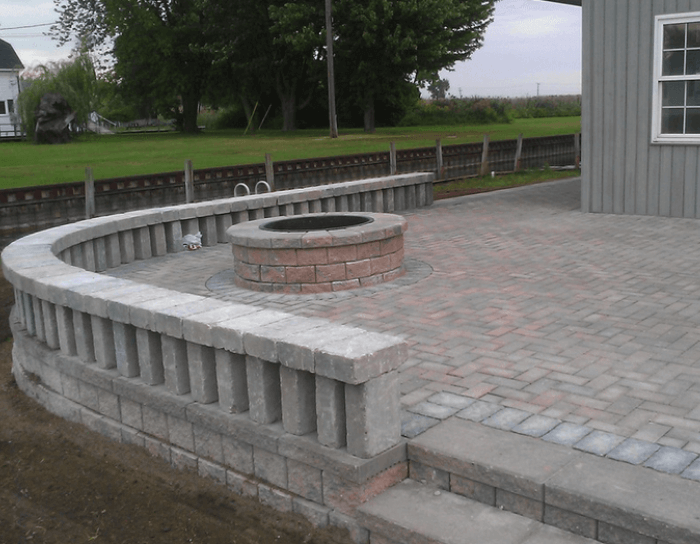 A brick patio with a fire pit in the middle
