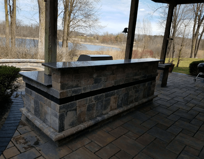 A large stone counter sits on a patio overlooking a lake