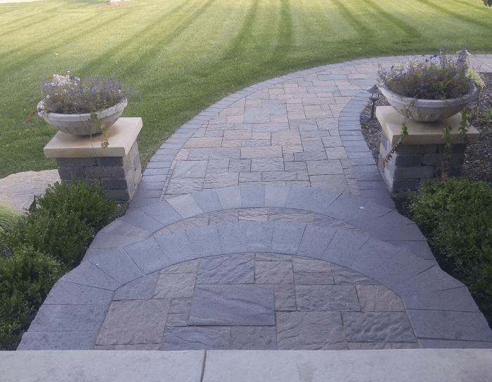 A brick walkway leading to a lush green lawn