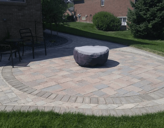 A round ottoman sits on a brick patio