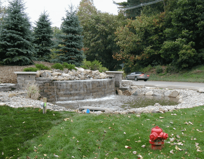 A red fire hydrant sits in front of a waterfall
