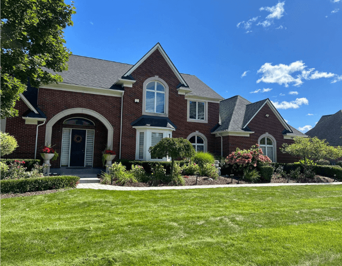 A large brick house with a lush green lawn in front of it