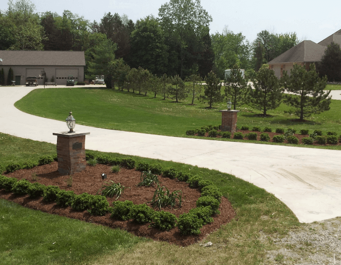A driveway with a brick pillar in the middle of it