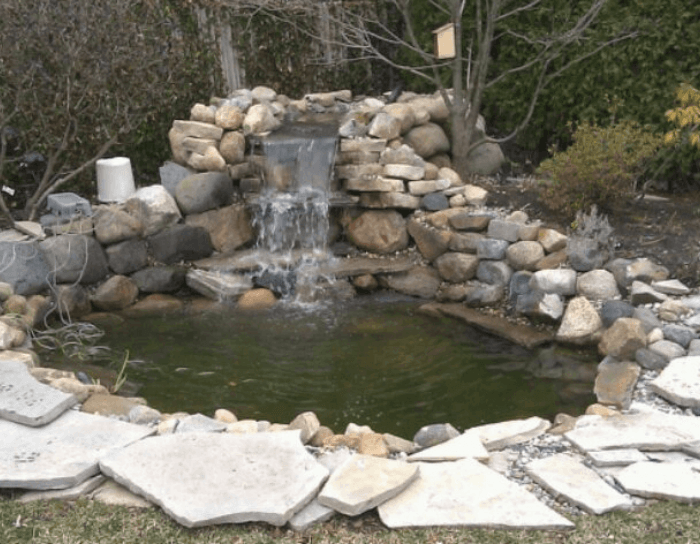 A waterfall is surrounded by rocks and a pond