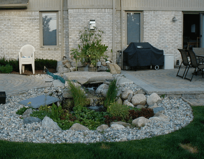 A patio area with a waterfall and a grill