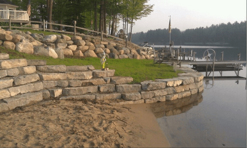 A large rock wall along the shore of a lake