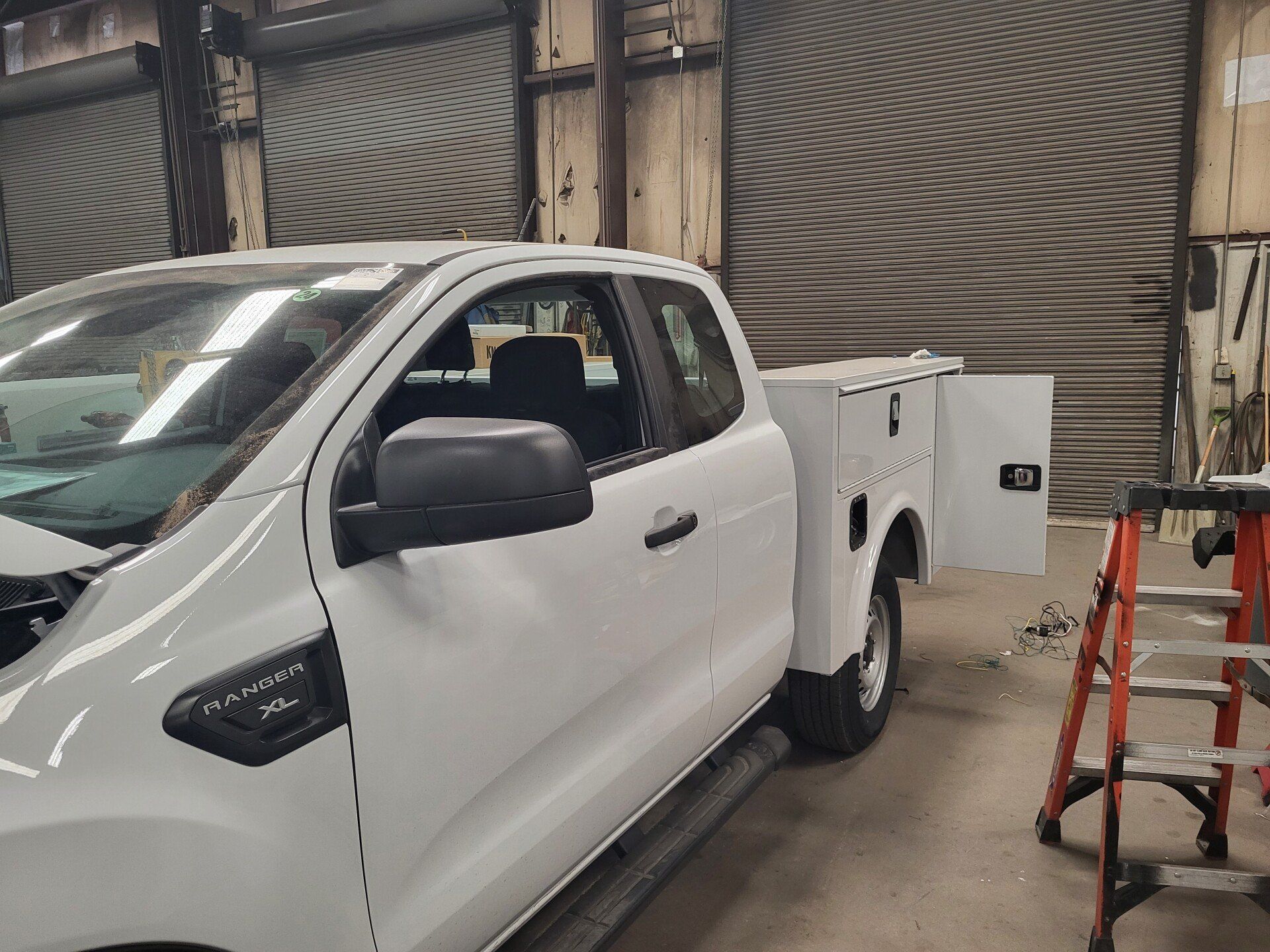 White work truck with side tool box in a garage.