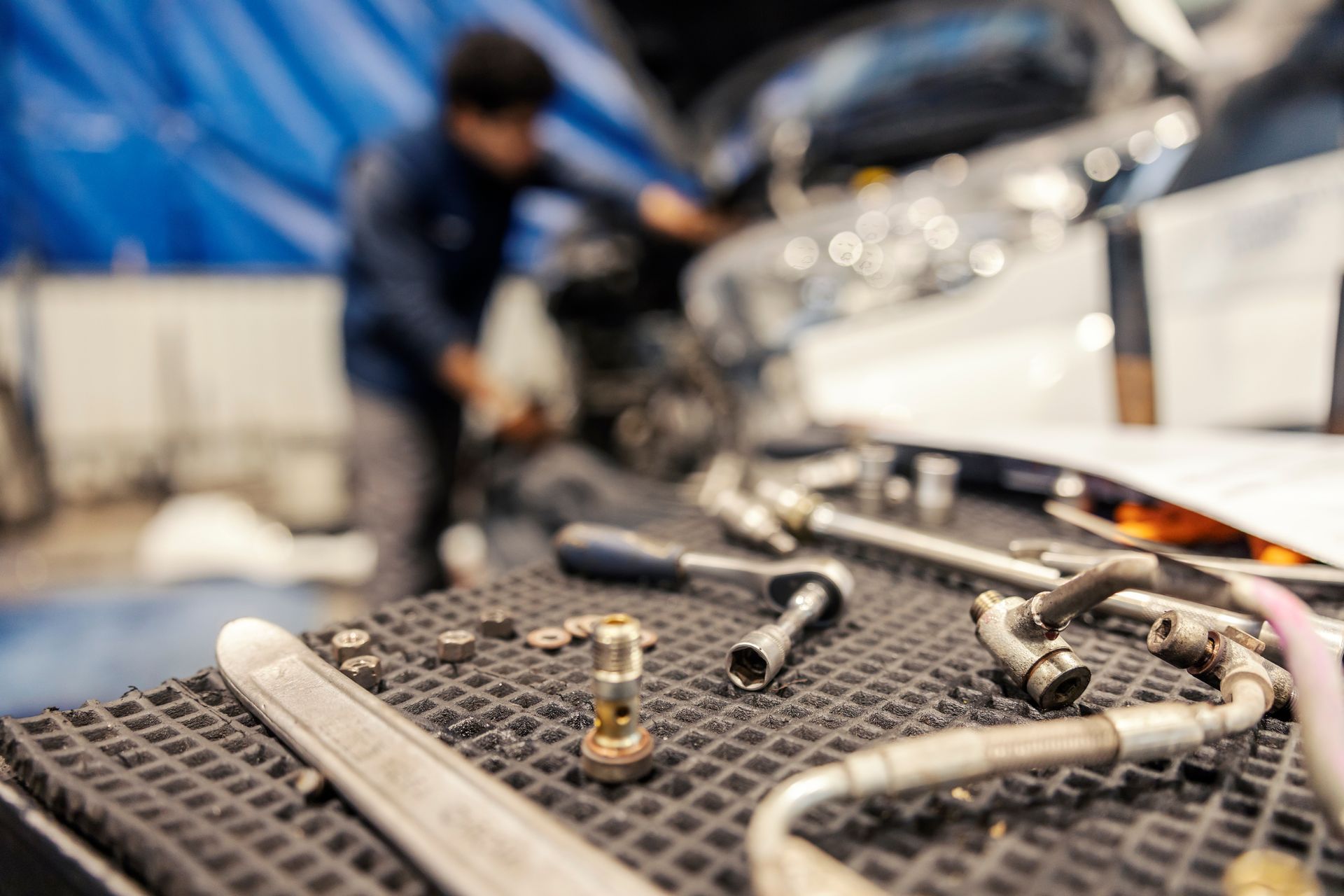 Truck equipment technician working in a shop with hand tools and hydraulic fittings on a workbench
