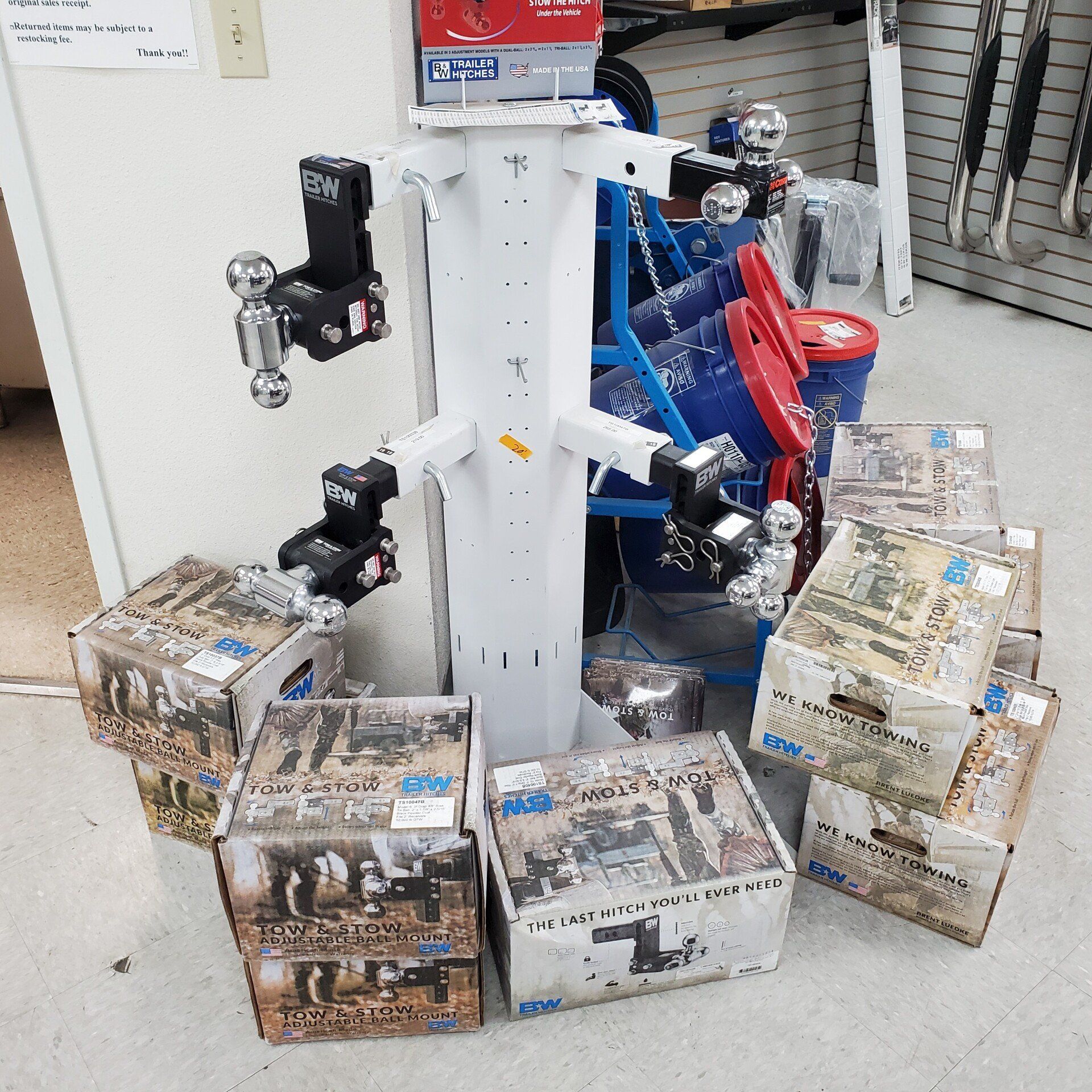 A display of trailer hitches and related parts, with boxes stacked in front of them.