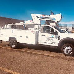 White utility truck with aerial lift in front of a building on a sunny day.