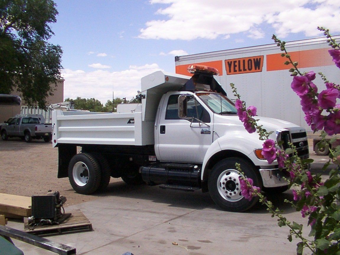 White dump truck parked outside, near a building with 