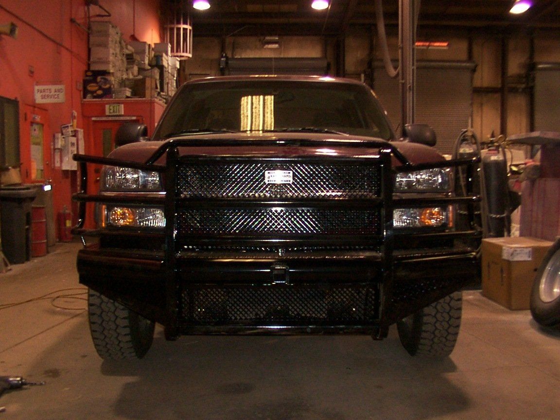 Dark red truck with black grille guard and bumper, in a garage setting.