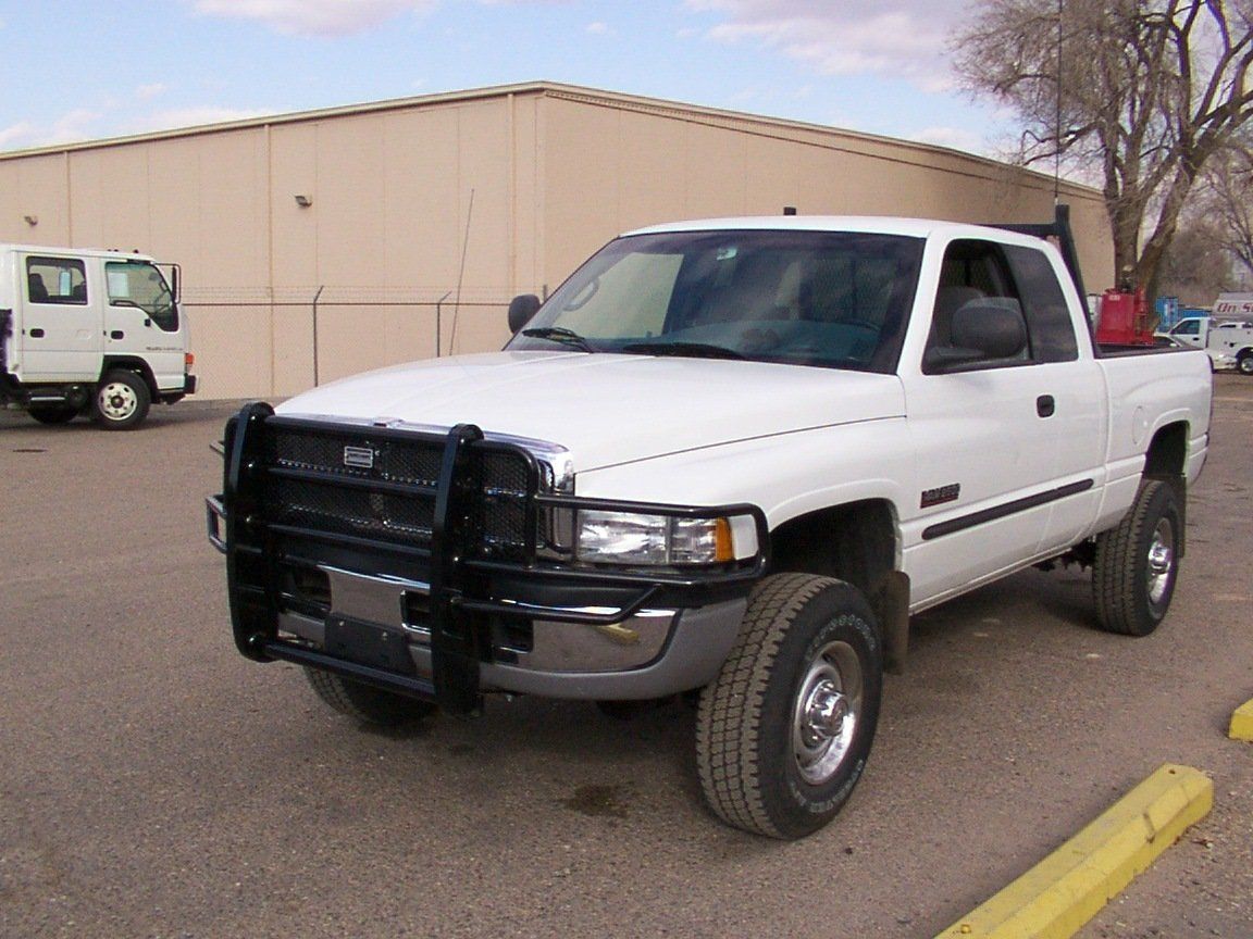 White Dodge Ram pickup truck with a black brush guard parked outside a building.