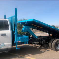 A white pickup truck with a blue dump bed in an outdoor setting.