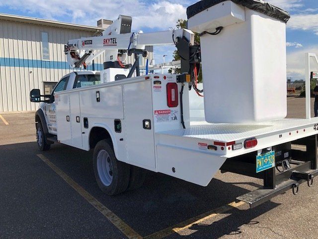 White utility truck with bucket lift parked in a parking lot.