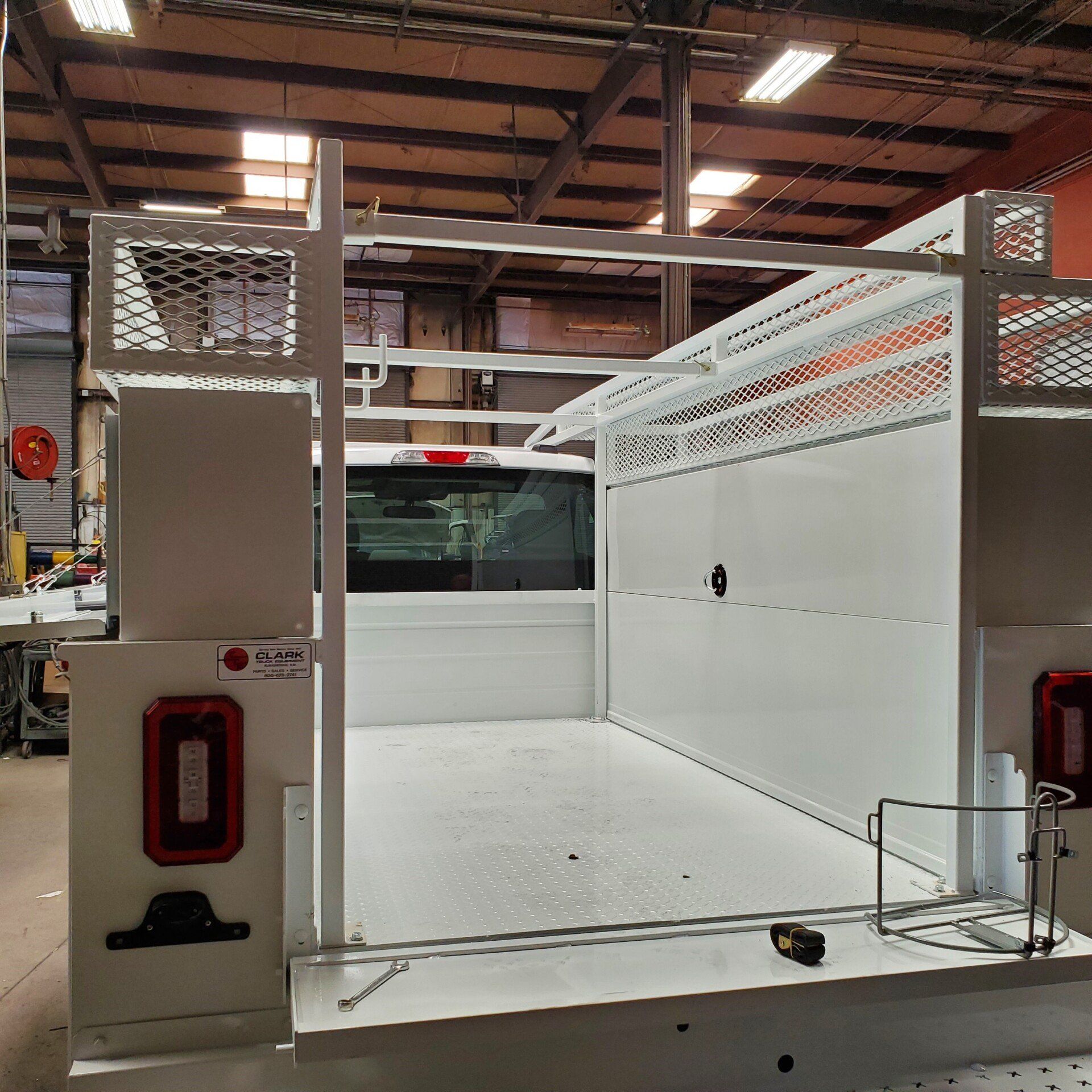 White truck bed with metal framework, interior white walls, and red taillights in a warehouse.