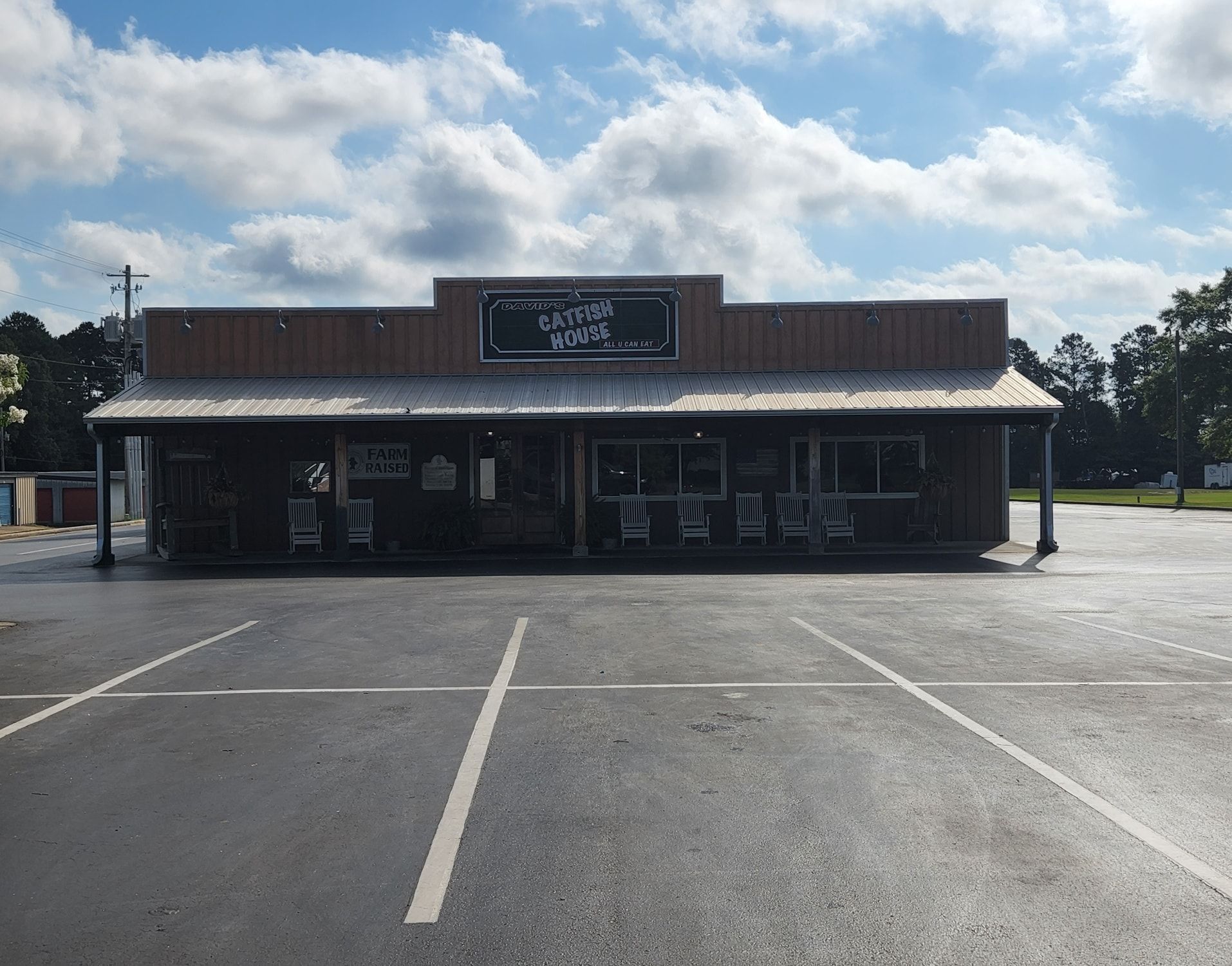 A white house with a gray roof is sitting on top of a lush green field.