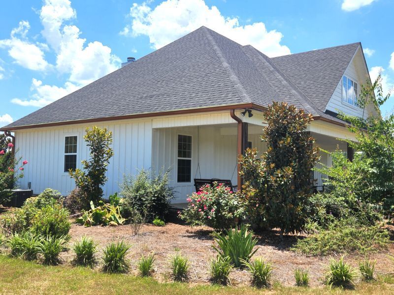 A white house with a black roof and a porch