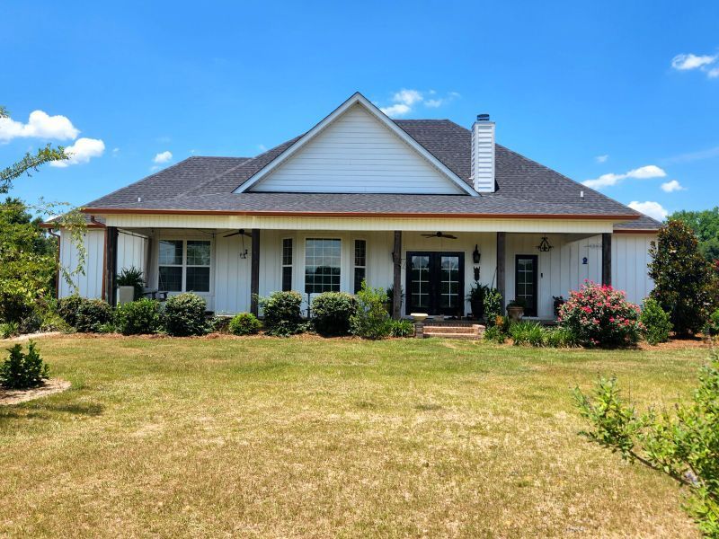 A white house with a black roof and a large porch