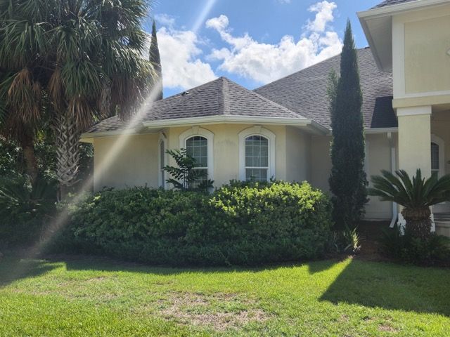 A house with a lot of bushes and trees in front of it