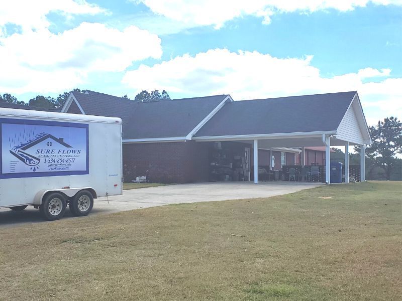 A white trailer is parked in front of a house.