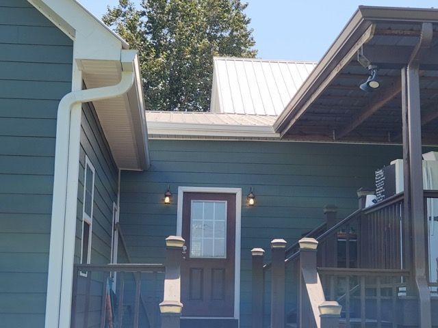 A blue house with a porch and a white roof
