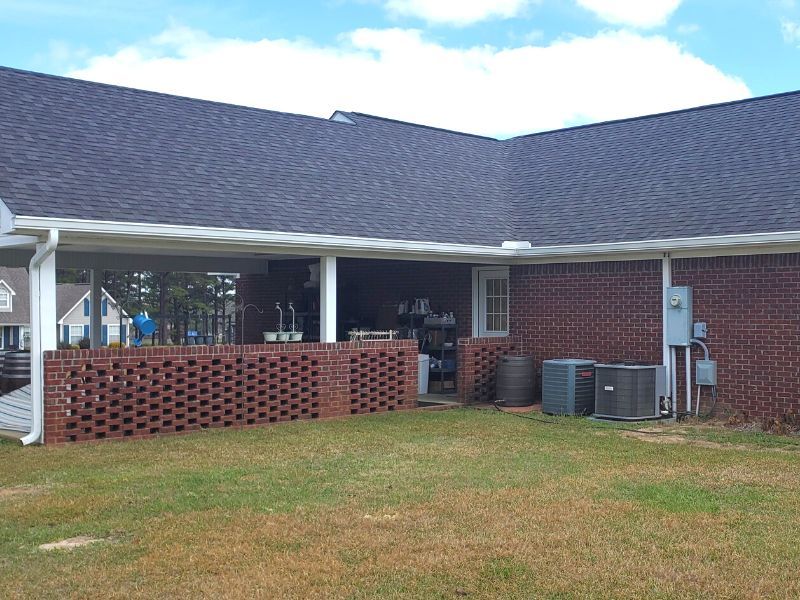 A brick house with a covered patio and a brick wall in the backyard.