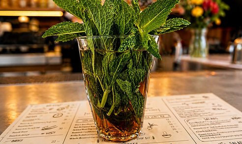 A glass filled with fresh mint sprigs on a bar counter with a menu underneath.