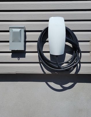 Une lumière blanche et un cordon noir sont posés sur un banc en bois.