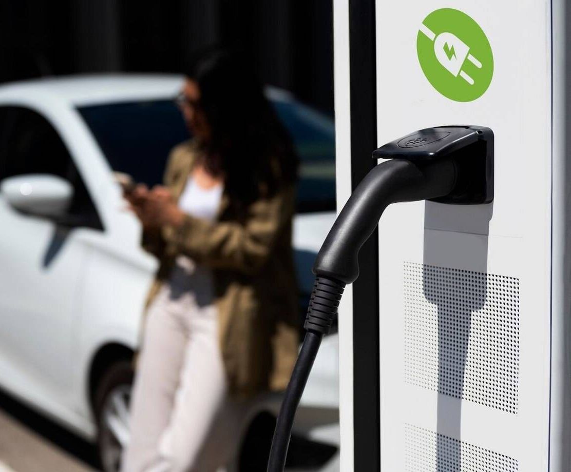Une femme charge sa voiture électrique à une borne de recharge
