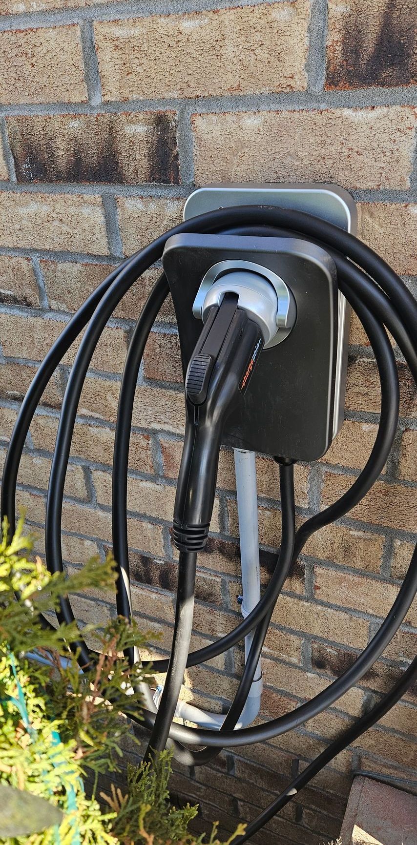 Un gros plan d'une borne de recharge pour véhicule électrique sur un mur de briques.