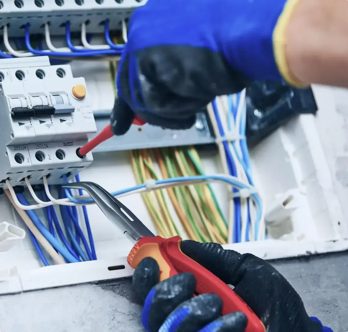 Un électricien travaille sur un circuit imprimé avec un tournevis