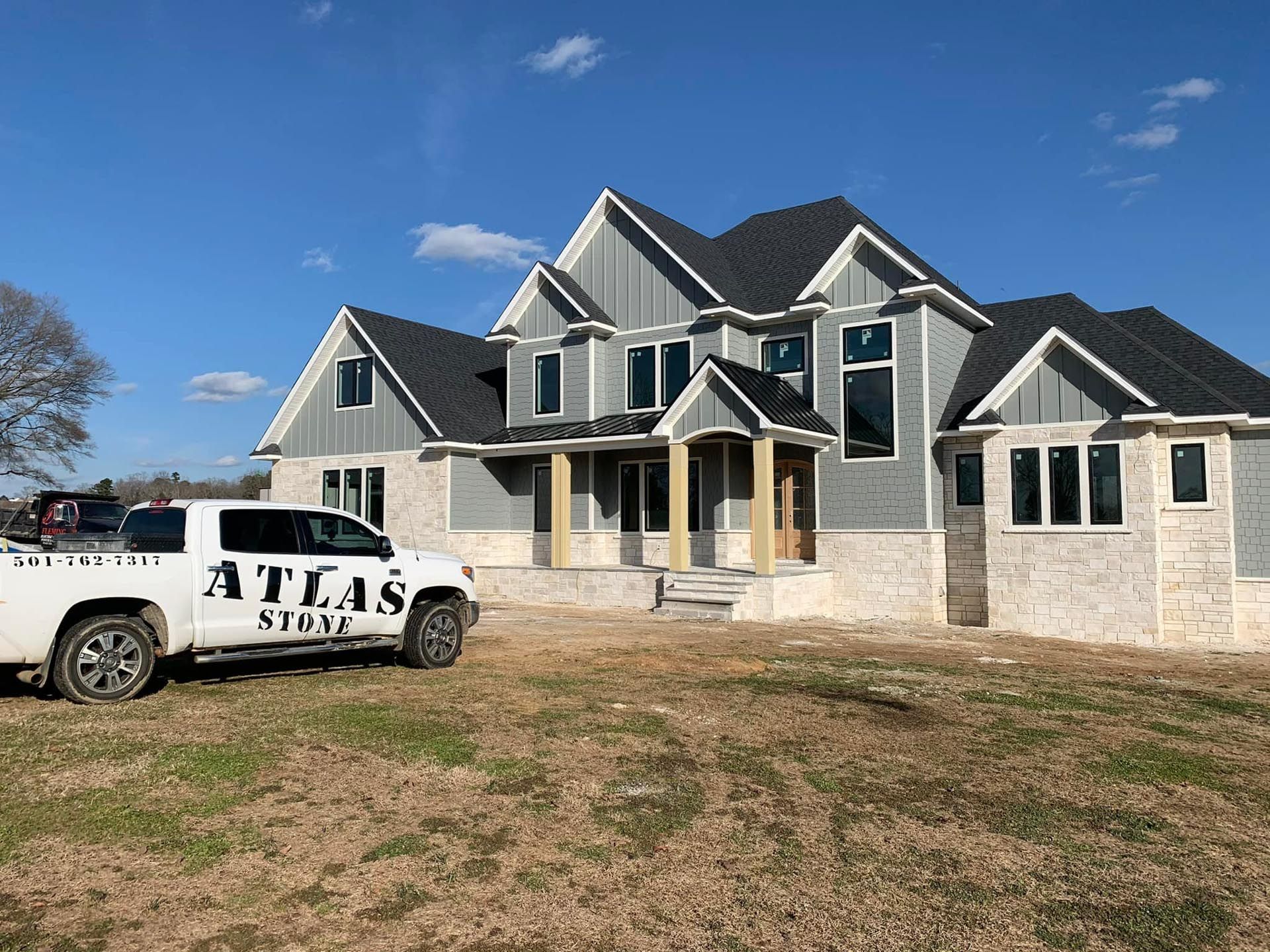 A white atlas truck is parked in front of a large house.