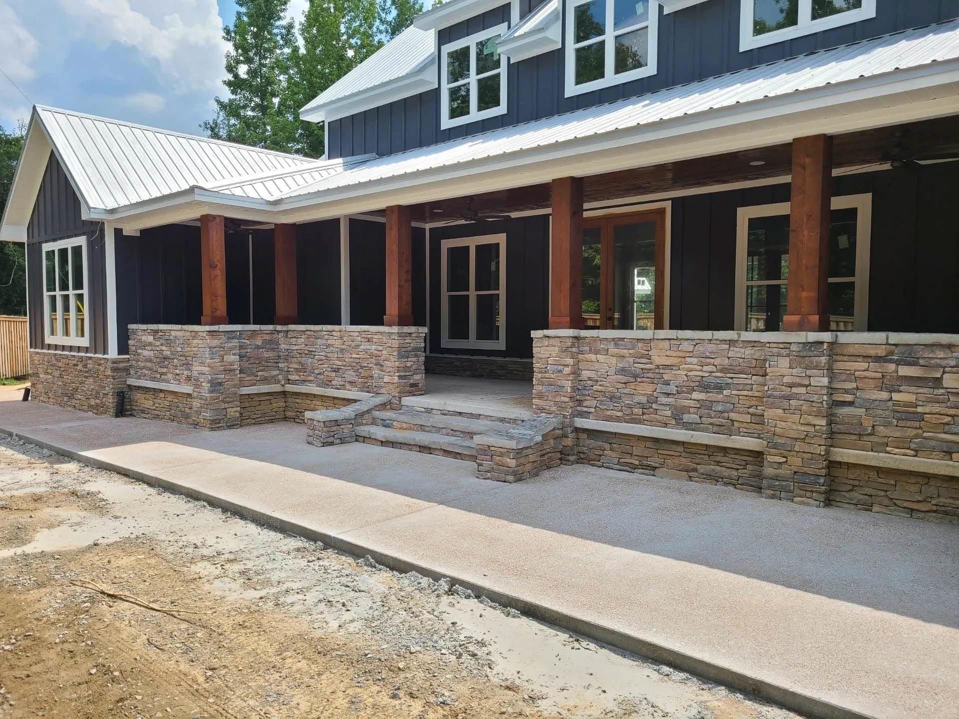 A large house with a large porch and a stone wall.