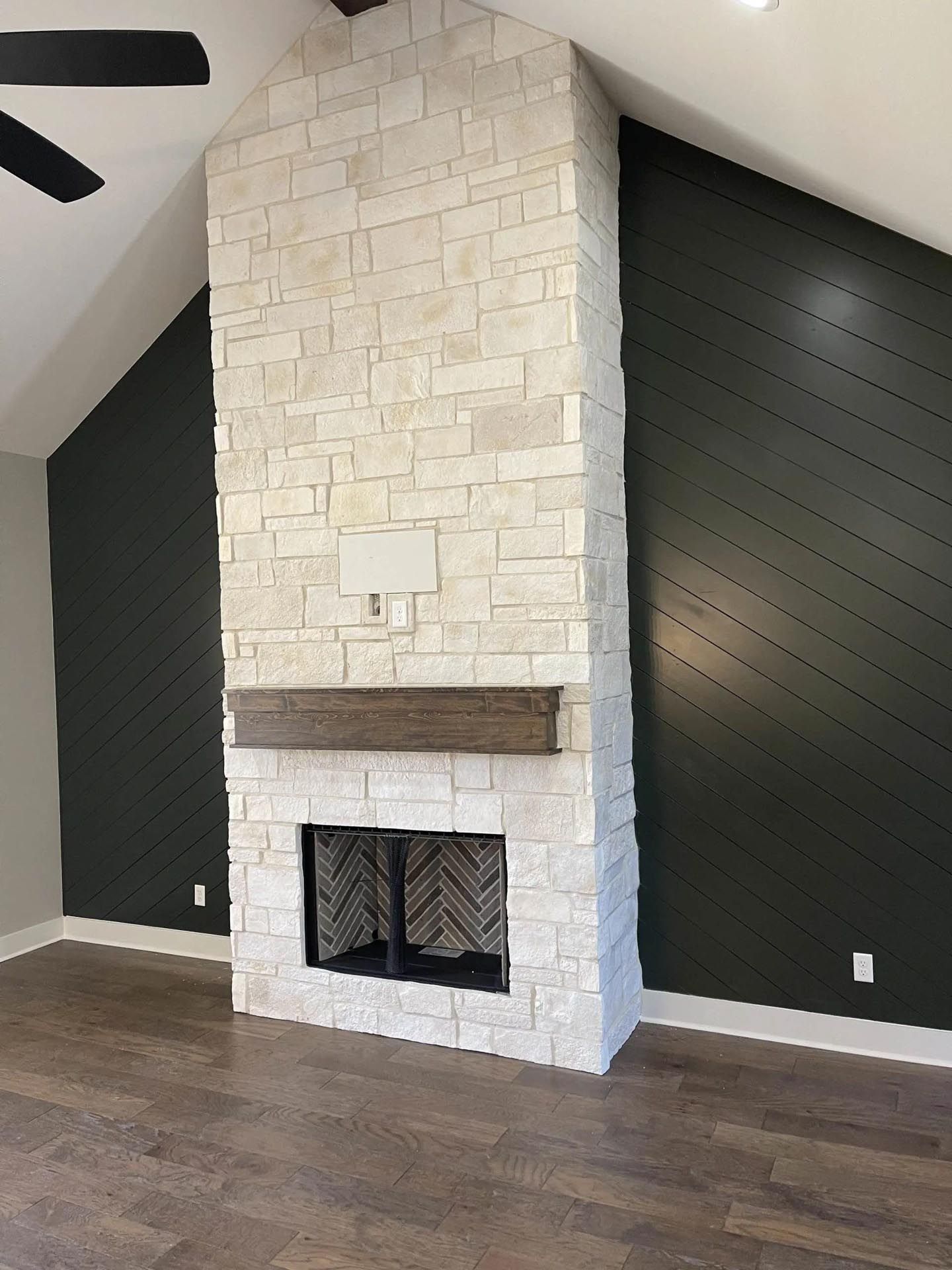 A living room with a fireplace and a ceiling fan.