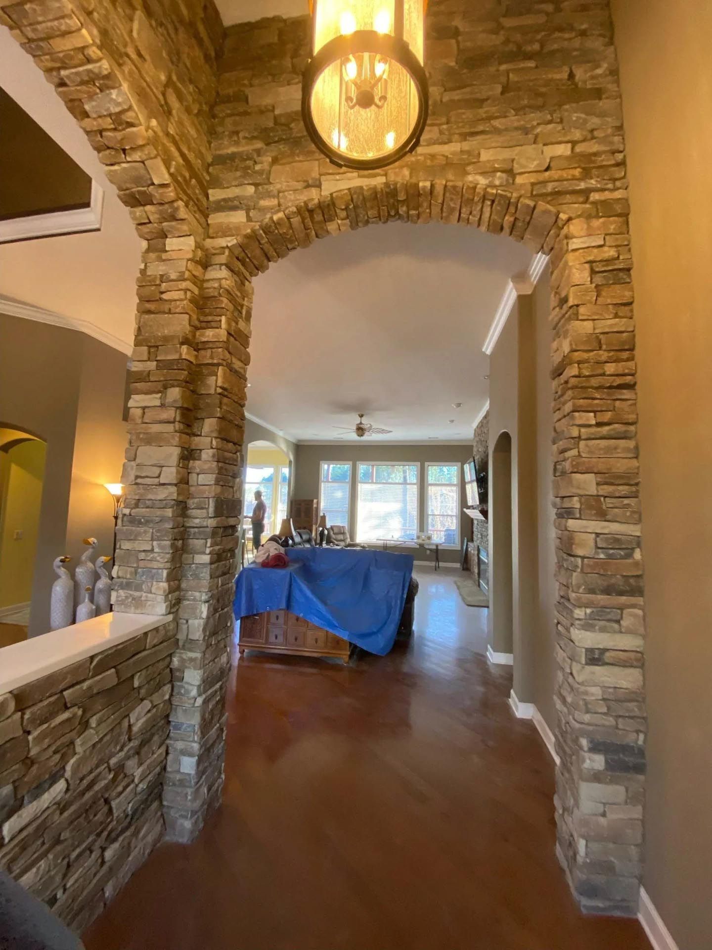 A hallway with a stone archway leading to a living room.