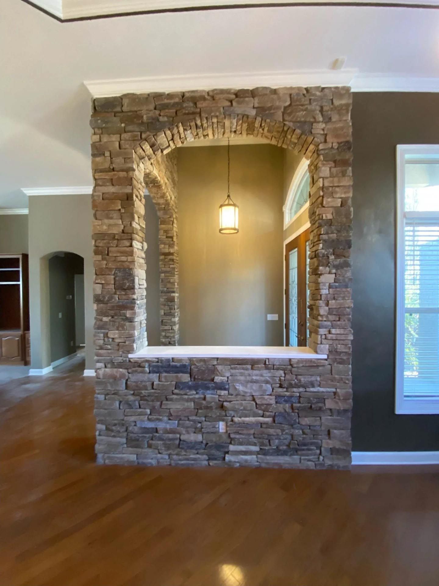 An empty living room with a stone wall and a window.