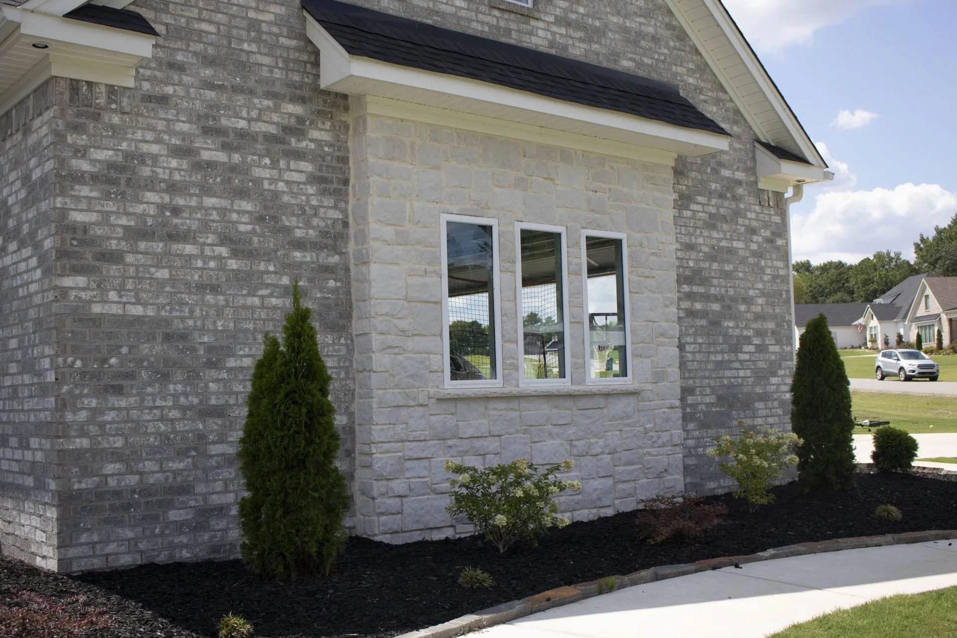 A brick house with a white window and a black roof
