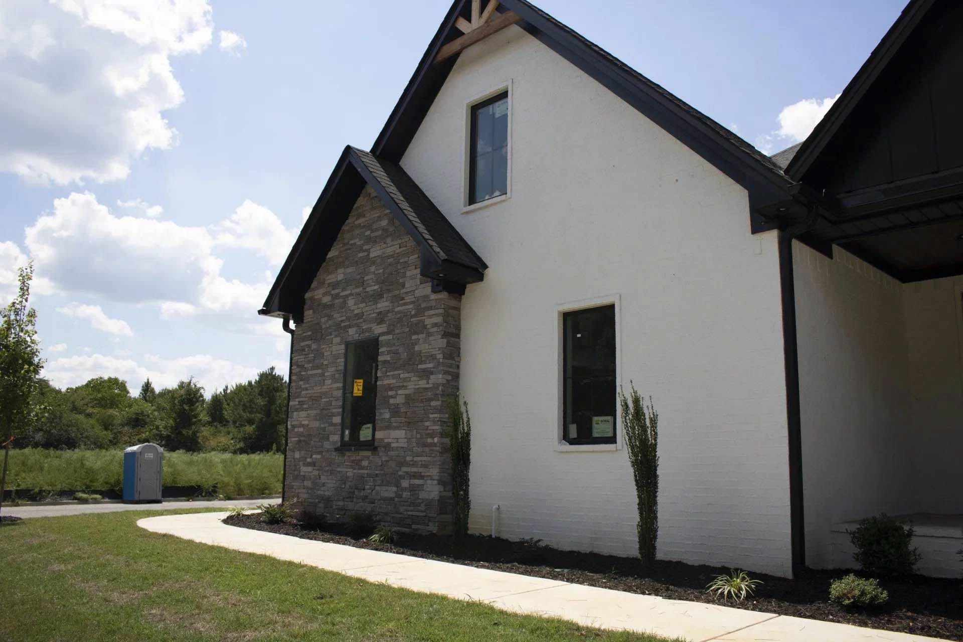 A white house with a black roof and a walkway leading to it