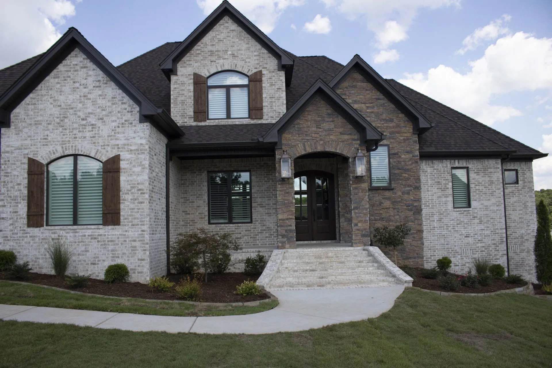 A large brick house with a black roof and shutters